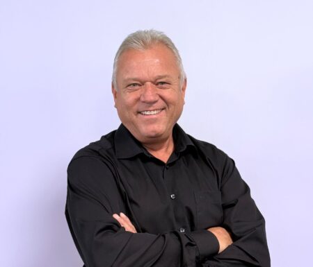 Portraitfoto eines Mannes mit verschränkten Armen und dunklem Hemd